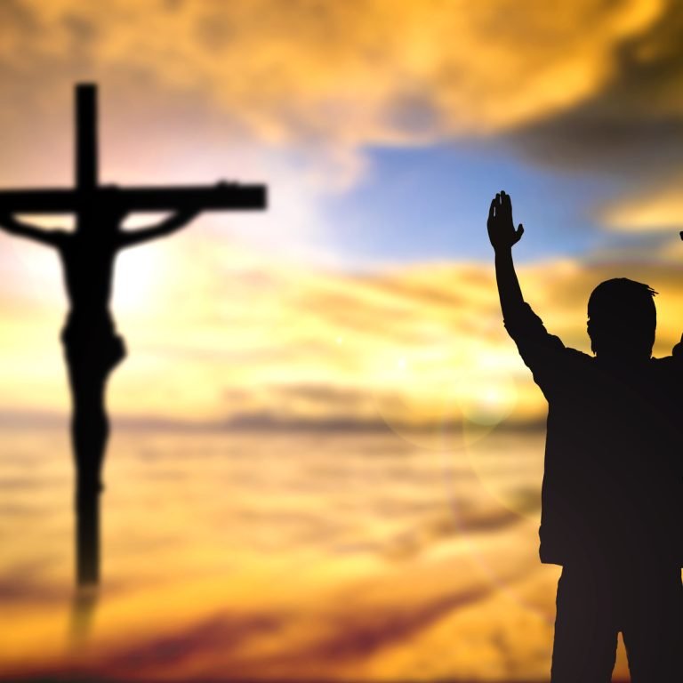 Silhouette of man with raised hands over blur cross concept for religion, worship, prayer and praise.